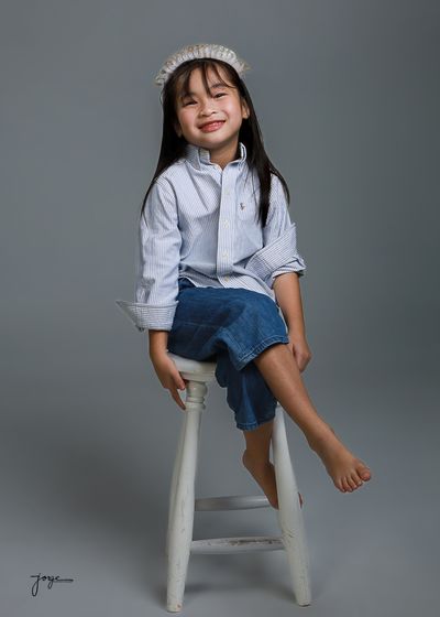A laughing child perched on a wooden stool