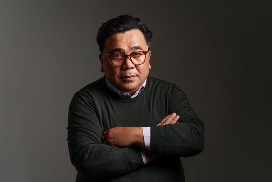 A man with arms folded, photographed in profile light
