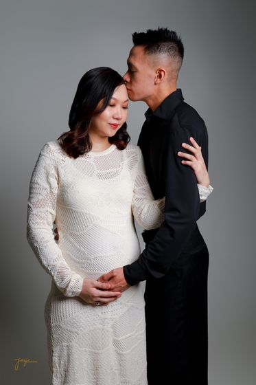 An expectant couple in white and black, foreheads together