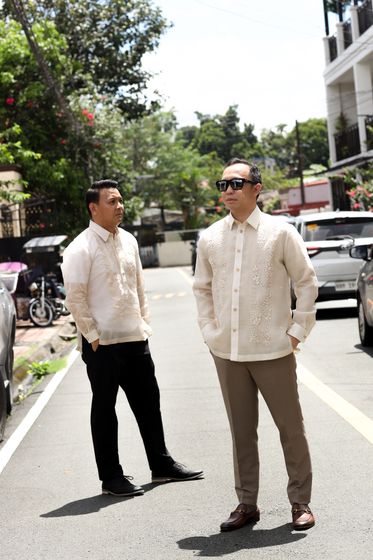 Two men in barong Tagalog on a tree-lined street