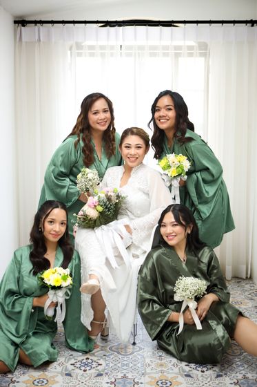 A bride and her bridesmaids in green robes, laughing together